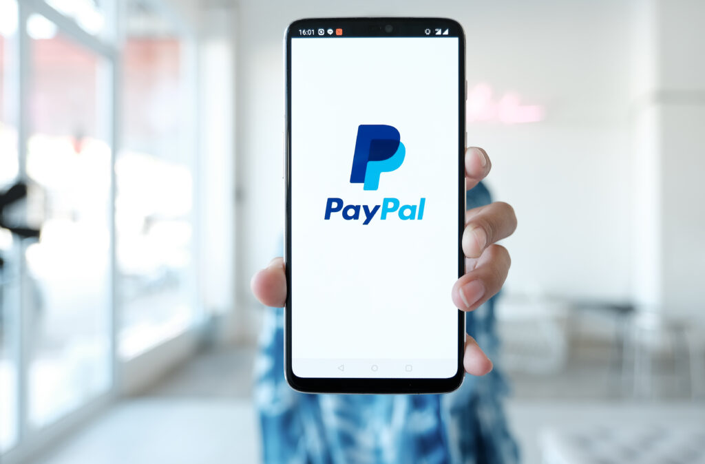 Woman hands holding mobile with PayPal apps on the screen.